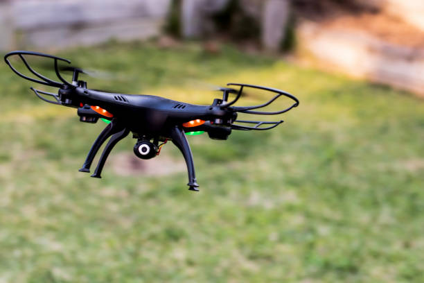 istock Black drone quad copter with camera landing on a green grass take off. Drone photography videography aerial wireless technology 1401347281
