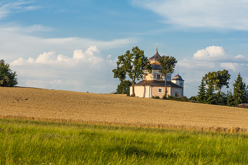 Beautiful 17th century baroque church of Saint Barbara. Building of octagonal shape is standing on the hill in the middle of fields under the setting sun. Procevily village near Breznice town in the Czech Republic