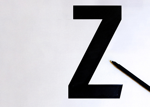 Hand written letter Z — font making process, black letter on paper background.