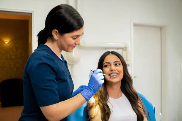 beautiful young woman with dental brackets, sitting in dentist chair and having checkup