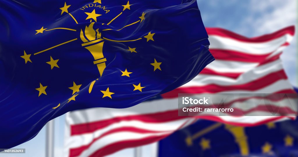 The Indiana state flag waving along with the national flag of the United States of America. The Indiana state flag waving along with the national flag of the United States of America. In the background there is a clear sky. Indiana is a U.S. state in the Midwestern United States Indiana Stock Photo