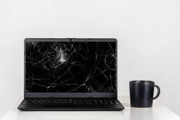 istock a laptop with a broken screen and a black mug of tea on a table against a white wall 1401353670