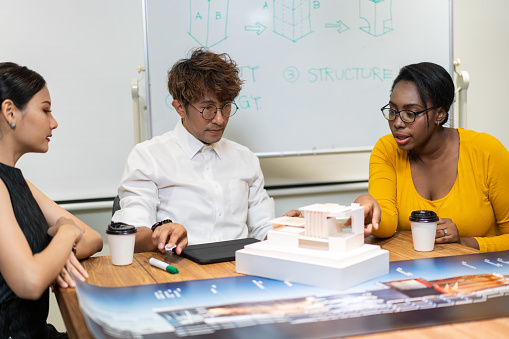 Group of diversity architect designer discuss and critic architecture design project in the office. man presenting and explaining house model to client. team brainstorming for work process