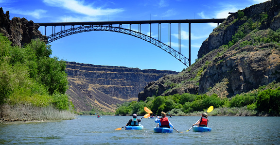 Kayaking on river in canyon with bridge spaning distance adventure