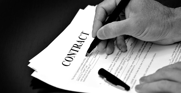 Contract on desk with black pen being signed by person