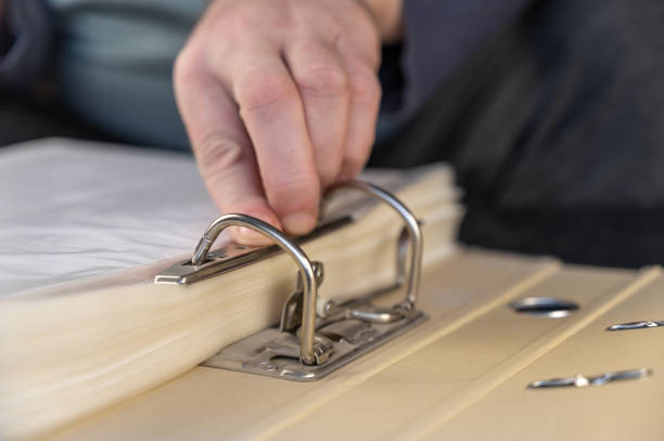 A man closes a metal binder with his hand. An open gray document folder. Close-up. Selective focus