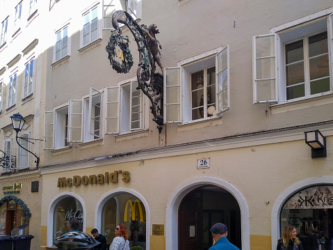 Getreidegasse, in Salzburg, Austria on a bright spring morning.  There are people walking past outside of a McDonald's.