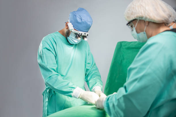 ärzte performing chirurgie - chirurgenbrillen stock-fotos und bilder