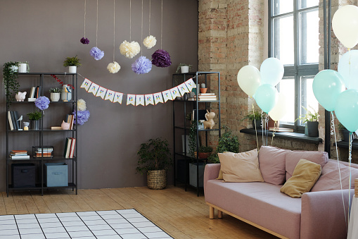 Horizontal image of modern domestic room decorated with helium balloons and poster with congratulation for birthday party