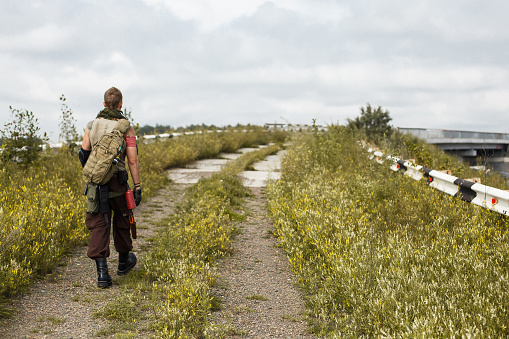 a man walks along an abandoned and grassy bridge