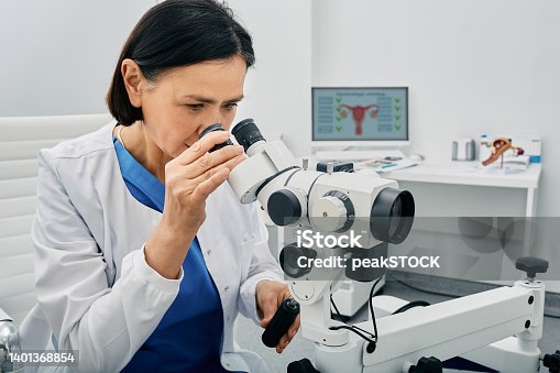istock Experienced gynecologist woman sitting near colposcopy in her gynecological office. Profession of gynecologist for women's health 1401368854
