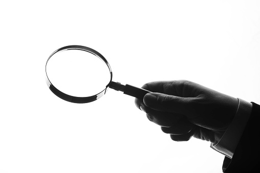 Holding magnifying glass on white background.