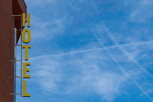 Vintage hotel sign. Vertical hotel sign mounted on the brick facade of the hotel. Copy space for writing on blue sky