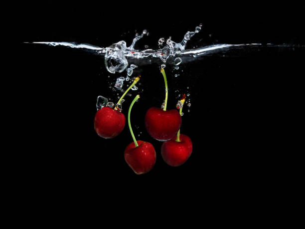 istock Red sweet cherries under water isolated on black background 1401377058