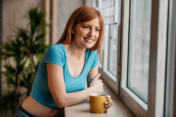istock Woman is looking through the window and drinking coffee 1401380002