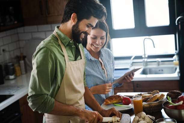 istock Beautiful young couple is using a digital tablet and smiling while cooking in kitchen at home 1401380221