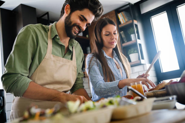 istock Beautiful young couple is using a digital tablet and smiling while cooking in kitchen at home 1401380224