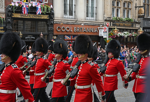 The scene in London's Whitehall Rd during the Platinum Jubilee Pageant through the streets of London, guards pass a store sign \