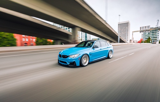 Seattle, WA, USA \nJune 4, 2022 \nBlue BMW M3 driving the highway next to a concrete overpass