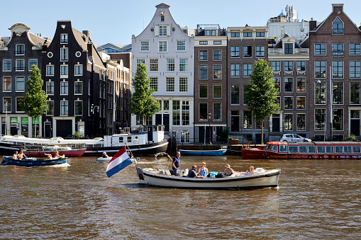 People wait for the city tour boat by Damrak canal in Amsterdam, Netherlands. Amsterdam is the capital city of The Netherlands.