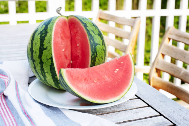 istock Seedless watermelon with a slice on a table on a wooden terrace. 1401385508