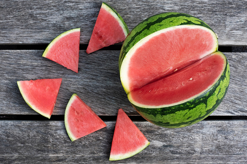 Seedles watermelon and slices on wooden background, summer concept.