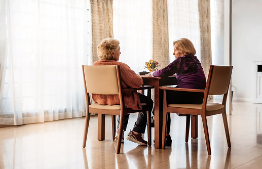 general view of two elderly sisters talking intimately in a nursing home. concept of family and old age. alzheimer's disease.
