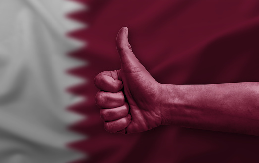 Hand making thumb up painted with flag of qatar