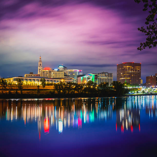istock Hartford Downtown Nightscape with Reflections on the Connecticut River, Glowing Lights Bokeh on the blue water. Stormy cloudscape illuminated by the city lights. 1401392315