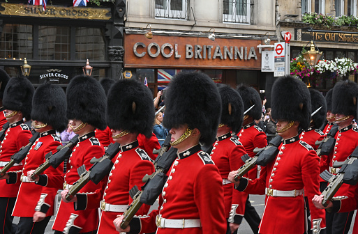 The scene in London's Whitehall Rd during the Platinum Jubilee Pageant through the streets of London, guards pass a store sign \