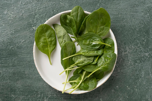 Spinach juicy leaves on a white plate, top view