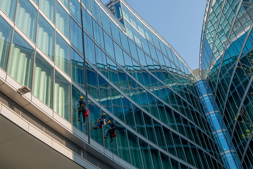 Milan Italy march 29 2021: skilled glass cleaners who lower themselves with slings from above