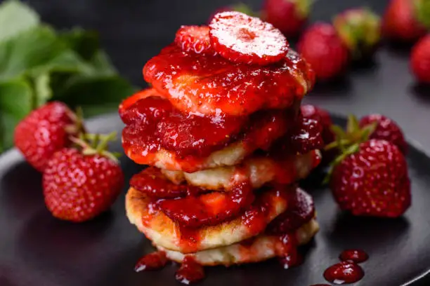 Cottage cheese pancake with strawberry jam on a concrete background