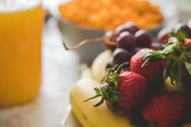 Healthy fresh fruit salad in a bowl with an orange juice for breakfast