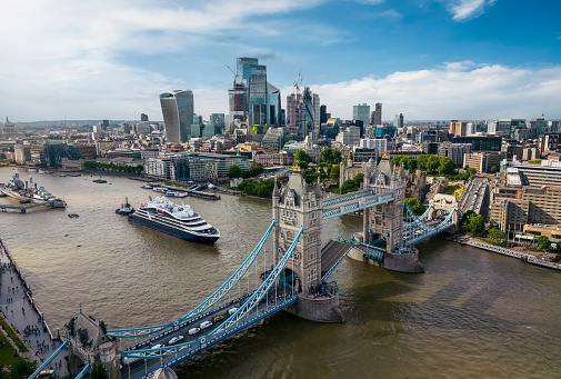 Panoramic aerial view of the cityscape of London, England, with the lifted Tower Bridge and a ship passing under