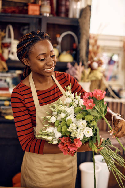 istock Happy black woman using fresh flowers while making bouquet at flower shop. 1401400348