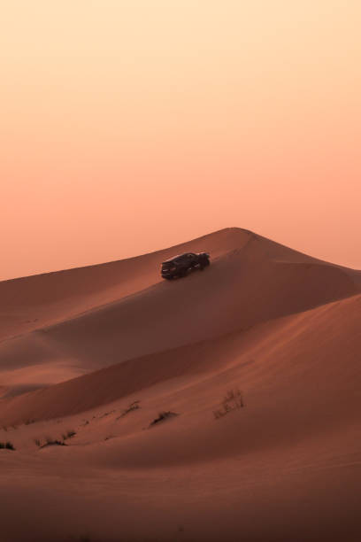 suv jeep à la colline de dunes de sable du désert au coucher du soleil - ras al khaimah photos et images de collection