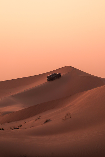 SUV Jeep at Desert sand dune hill during sunset