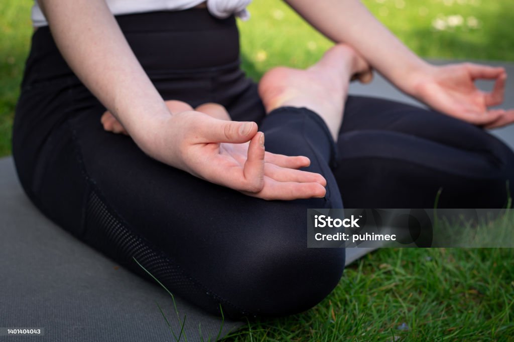 A young woman practices yoga in nature, on the grass in the yard. A young woman practices yoga in nature, meditates, sitting on a rug in the yard, close up. 16-17 Years Stock Photo