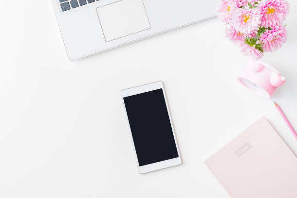istock Flat lay home office desktop with laptop, pink flowers in a vase, notebook, tablet, office supplies on a light background. Top view mockup tablet with blank screen 1401404076
