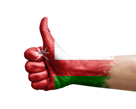 Hand making thumb up painted with flag of oman