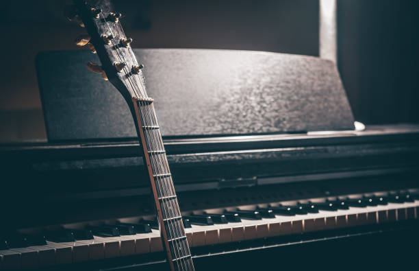 Guitar and electronic piano in a dark room close-up.