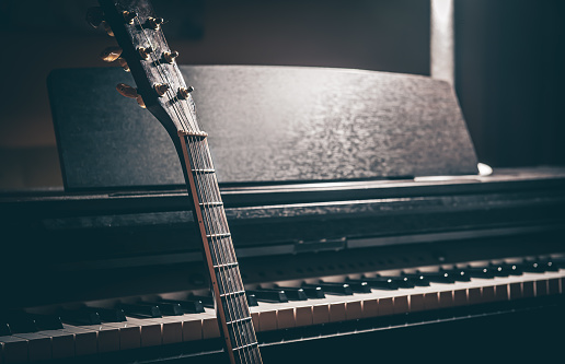 Guitar and electronic piano in a dark room close-up, copy space.