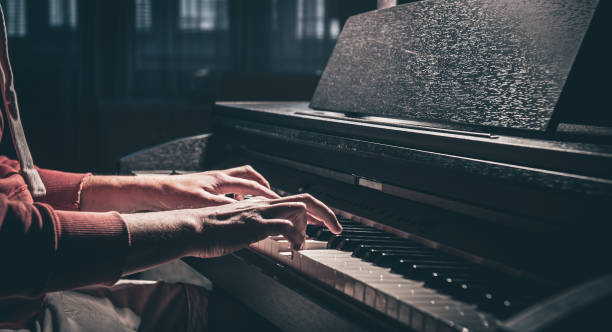 un uomo suona un pianoforte elettronico in una stanza buia. - piano piano key orchestra close up foto e immagini stock