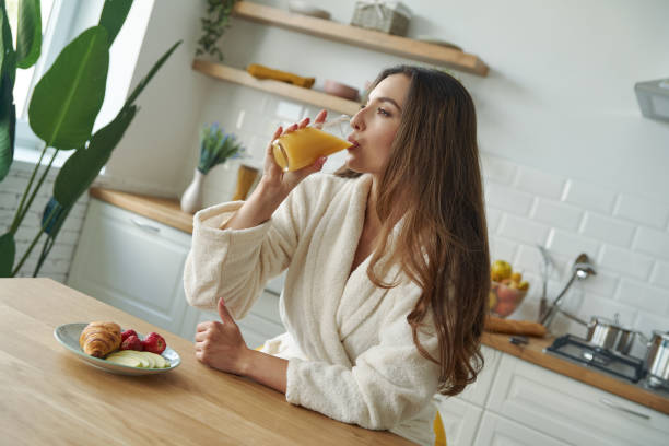 istock Attractive young woman in bathrobe having breakfast at the modern kitchen 1401406165