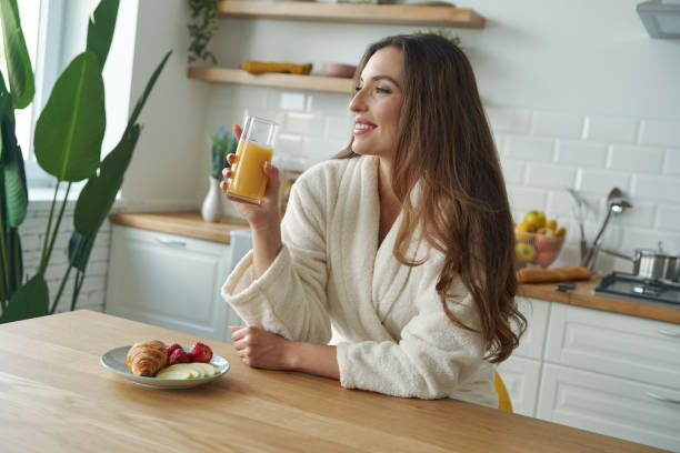 istock Happy young woman in bathrobe having breakfast at the modern kitchen 1401406167