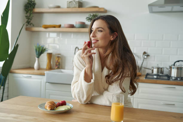 istock Happy young woman in bathrobe having breakfast at the modern kitchen 1401406171