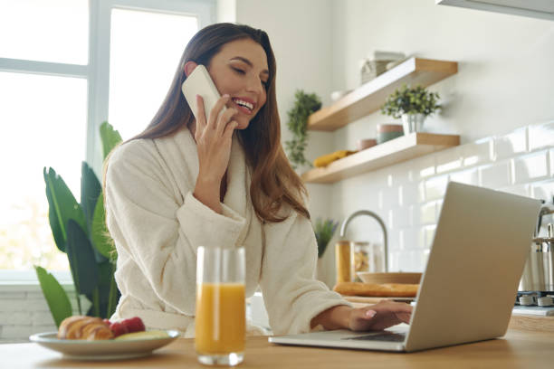istock Beautiful woman using laptop ant talking on mobile phone 1401406247