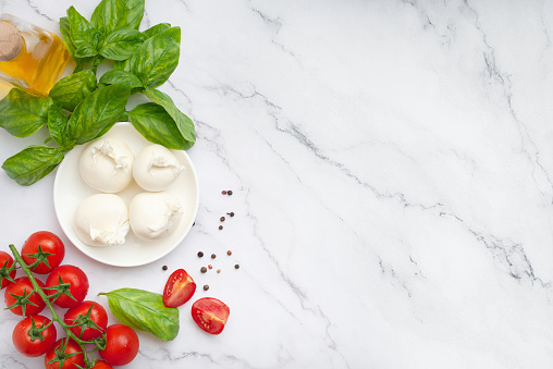 Mozzarella with tomatoes, butter and basil on a white background