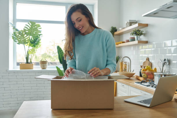 istock Attractive young woman unpacking box while standing at the domestic kitchen 1401406344